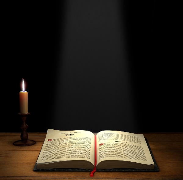 Open Bible on a table with a candle with copy space above